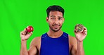 Asian man, apple and donut on green screen in choice for diet, sweet or unhealthy eating against a studio background. Male person with food or snack for meal decision in fitness on mockup space