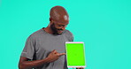 Advertising, black man with tablet and pointing against a blue background. Marketing or tech, product placement or promotion and African male person pose for mockup space against a chroma key