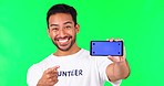 Green screen, pointing  and man with phone mockup to volunteer, charity and community service app. Technology, social media and portrait of male person for ngo, nonprofit and donation advertising