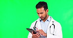 Surgeon, scroll and man on tablet in green screen for cardiology in studio background with indian. Male doctor, technology and reading with thinking at clinic for healthcare on email, app or online.