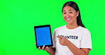 Tablet, marketing and a woman volunteer on green screen background in studio holding a display with tracking markers. Portrait, charity website and a happy young asian person holding chromakey