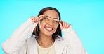 Woman, face and spectacles for fashion in studio with smile, confidence and happy with frame by blue background. Girl, model or student with designer eyewear, glasses or lens for vision in portrait