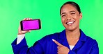 Green screen, pointing and face of a woman with a phone for communication, handyman work or app. Smile, portrait and a female maintenance worker with space on a mobile isolated on a studio background