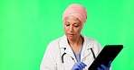 Doctor, woman and tablet by green screen, typing or reading for info, insurance or chat in mockup. Islamic female medic, digital touchscreen or app for health, wellness or communication at clinic job