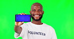 Smartphone, mockup with green screen and volunteer, black man and community service with app on studio background. Website sign up, register for charity work and male person help and tracking marker