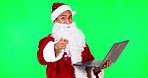 Santa Claus, Christmas and man on laptop on green screen for holiday, festival and celebration. Studio, festive season and portrait of male person on computer for gifts, present and online checklist