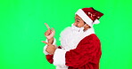 Christmas, Santa and pointing with man on green screen for presentation, idea and show.  Deal, advertising and space with portrait of person on studio background for xmas, festive and holiday season