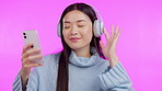 Music, dance and phone with an asian woman in studio isolated on a pink background for streaming audio. Smile, freedom and headphones with a happy young female person listening to a radio playlist