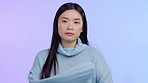 Portrait, serious and face of a woman upset or unhappy with arms crossed on a purple background. Sad asian female person with bad attitude, negative expression and sulking about problem in studio