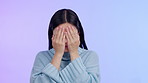 Face, woman and covering eyes for fear, anxiety or mental health problem on purple background. Portrait of scared asian person peek through hands for scary surprise, danger and horror or shame