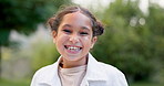 Child, face and girl laughing outdoor in a garden, park or green environment for fun and happiness. Portrait of a young female latino kid with a positive mindset, cute smile and nature to relax