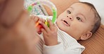 Sweet, playing and cute baby with a toy on a blanket for child development, fun and entertainment. Happy, adorable and playful infant child relaxing on a bed in his nursery or bedroom at family home.