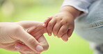 Finger, love and a mother holding hands with her baby outdoor in the garden closeup for trust, care or bonding. Morning, kids or family with a woman and infant child in a backyard together in summer