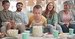 Blowing, birthday boy or big family with cake in celebration or house party with support, candles or love. Grandmother, grandfather or excited child eating baked desert with dad, mom or grandparents 