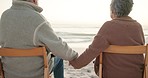 Sunset, beach and senior couple on chair by ocean for commitment, bonding and quality time. Love, travel and back of man and woman holding hands sitting for romantic holiday, vacation and anniversary