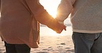 Sunset, beach and closeup of couple holding hands by ocean for commitment, bonding and quality time for love. Marriage, travel and man and woman relax for romance on holiday, vacation and anniversary