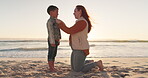 Summer, family and a mother with her son on the beach at sunset for travel, vacation or holiday together. Children, love and sea with a woman parent talking to her male child on the sand for bonding