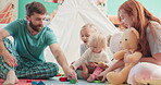 Happy, playing and a family with blocks in a house for bonding, building game or learning with a toy. Laughing, together and a mother and father with children and toys on the living room floor