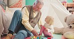 Toys, bonding and grandfather playing with a child in her playroom or nursery in their house. Happy, smile and senior man talking and helping his girl grandchild with building blocks in their home.