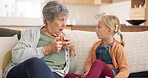 Conversation, relax and grandmother talking to a child while drinking a cup of tea in the living room. Communication, retirement and senior woman speaking to a little girl child on a sofa in her home