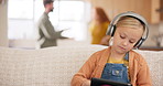 Tablet, headphones and parents fighting with a girl sitting on a sofa in the living room of her home during an argument. Sad, divorce or technology with a daughter and conflict of mother and father