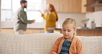 Sad, divorce and parents fighting with a girl sitting on a sofa in the living room of her home during an argument. Fear, stress or anxiety with a daughter watching conflict of her mother and father