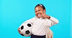 Girl child, soccer ball and studio for smile on face, thumbs up or backpack for sport, learning and blue background. Young female kid, school uniform or football with icon, sign language and portrait