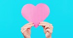 Blue background, showing and hands with a heart card for love, valentines day or care. Charity, creative or person with a romantic gesture with paper for support isolated on a mockup studio backdrop