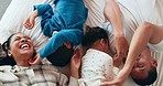 Laughing, happy and parents tickling their children on the bed while having fun, playing and bonding. Happiness, smile and young kids being playful with their mother and father in the bedroom at home