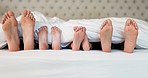 Bed, feet and family in the morning, relax and calm with sleeping, rest and dreaming at home. Mother, father or parents with children, kids or weekend nap on holiday, bedroom or chilling with bonding