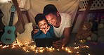 Dad and son at night on tablet in tent watching movies, online games and cartoon with fairy lights. Happy family, blanket and father with boy in bedroom on digital tech for bonding, relax and love