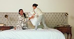 Pillow fight, mother and daughter on bed, playing and care with love, happy or funny game in family house. Mom, girl child and playful fight with bonding, quality time and laughing in bedroom in home