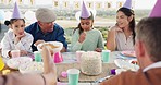 Family, food and girl with cake on birthday, celebration and party outdoors for social gathering. Event, lunch and happy mother, grandfather and children at picnic with dessert, presents and sweets