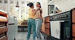 Playful, dance and mother with her kid in the kitchen jumping to music, playlist or radio at home. Happy, goofy and young mom singing and dancing to song or album with girl kid at their family house.