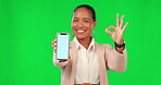 Okay sign, phone and woman on green screen for promotion, advertising mockup and success hands. Yes, excellence and happy face of business person on mobile app, ux design space and studio background 