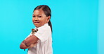 Bow tie, kids and an indian girl arms crossed on a blue background isolated in studio for fashion or trendy style. Portrait, children and an adorable female child posing indoor in a stylish outfit