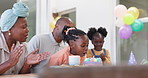 Birthday, kids party and applause with a black family in celebration of a girl child in their home. Parents, grandparents and children clapping while blowing candles on a cake at a milestone event