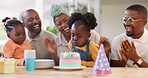 Birthday, children party and applause with a family in celebration of a girl child in their home. African parents, grandparents and kids clapping while blowing candles on a cake at a milestone event