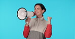 Megaphone, protest and motivation with a woman shouting in studio on a blue background for support at a rally. Noise, announcement and information with a young female speaker screaming propaganda