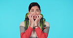 Hiking, nervous and scared woman in studio biting nails for fear, danger or anxiety and panic. Young female hiker with a backpack for travel, adventure or journey while lost on a blue background