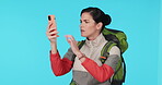 Phone, hiking and a woman in studio for connection, bad network or search for signal. Young female hiker with backpack and smartphone for travel, adventure or journey while lost on a blue background