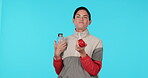 Exercise, eating and a woman with an apple and water on a blue background in studio for diet or nutrition. Fitness, sports and health with a happy young female athlete chewing fruit before a workout