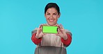 Fitness, phone and woman face with green screen in studio for gym, membership or promo on blue background. Smartphone, mockup and portrait of female personal trainer with app, menu or training guide