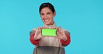 Woman, phone and show green screen in studio with face, smile and excited for promo by blue background. Lady, fashion model and smartphone with tracksuit for sport app, logo and branding in portrait