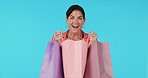 Wow, shopping bags or happy woman excited or surprised by prize in studio on blue background. Face portrait, smile or shocked girl with fashion gift or product on discount deals or promotional offer 