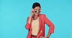 Sunglasses, fashion and wink with a model woman in studio on a blue background for trendy style. Portrait, shades and smile with a happy young female person looking playful while flirting in clothes