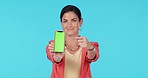 Green screen phone, studio and happy woman point at mock up design, brand presentation and show advertising space. Portrait, smartphone UI system and person gesture at commercial on blue background