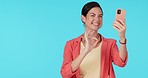 Business, video call and hello by woman in studio with perfect hand sign on blue background. Waving, call and female manager with smartphone for networking, social media and isolated advertising 