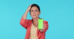 Phone, green screen and a confused woman on a blue background in studio scratching head in frustration. Portrait, doubt and chromakey on a mobile screen with a young female person asking a question