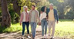 Nature, happy and couple walking with their parents in an outdoor park while on a weekend trip. Happiness, bonding and senior man and woman in retirement with their adult children in a green garden.